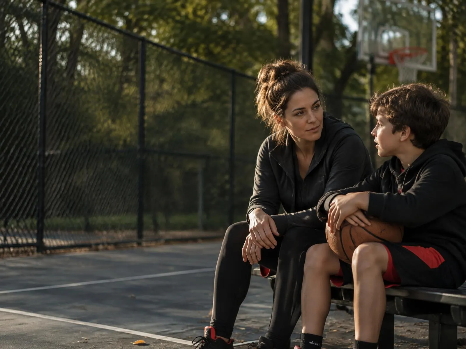 Original fictional parent listening to a child beside a basketball court